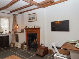 A living room with a fireplace and dining area at Carpenters Cottage Okehampton