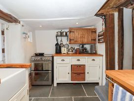 A kitchen with stove and wooden cabinets at Carpenters Cottage in Okehampton