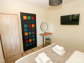 A bedroom with a wardrobe, table, and television at Just A Cottage in St Florence