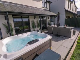 An outdoor patio with a hot tub and seating area at Just A Cottage in St Florence