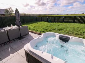 A garden with a hot tub and table set at Just A Cottage, St Florence