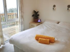 A bedroom with a bed and towels at Lowena Lodge Whitsand Bay Holiday Park near Millbrook