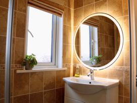A bathroom featuring a sink, mirror, and window at Lowena Lodge Whitsand Bay Holiday Park near Millbrook