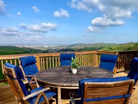 An outdoor seating area with a round table and chairs at Lowena Lodge Whitsand Bay Holiday Park near Millbrook