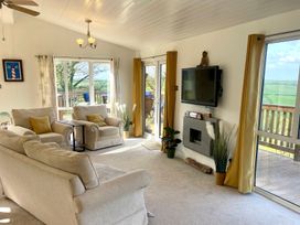 A living room with sofas and a television at Lowena Lodge Whitsand Bay Holiday Park near Millbrook