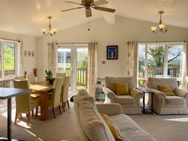 A living room with a dining table and chairs, sofa, and a coffee table at Lowena Lodge Whitsand Bay Holiday Park near Millbrook