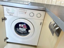 A washing machine inside a cabinet at Lowena Lodge Whitsand Bay Holiday Park near Millbrook