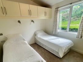 A bedroom with two beds and a window at Lowena Lodge Whitsand Bay Holiday Park near Millbrook