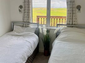 A bedroom with two beds and a view of the countryside at Lowena Lodge Whitsand Bay Holiday Park near Millbrook