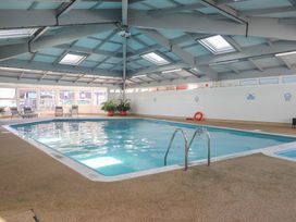 An indoor swimming pool with deck chairs at Lowena Lodge Whitsand Bay Holiday Park near Millbrook