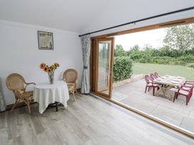 A dining room with a table and chairs leading to outdoor seating at Owl Barn in Banbury