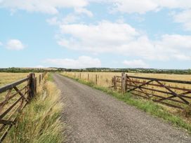 A gravel road between two wooden gates at Owl Barn in Banbury