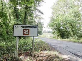 A sign marking the entrance to Farnborough with trees and a road in the background