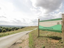 A sign for Burton Dassett Hills with grazing livestock at Burton Dassett Hills in Banbury