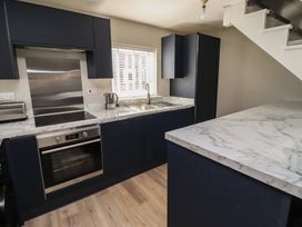 A kitchen with blue cabinetry and marble countertops at 3 Longstone Park Beadnell