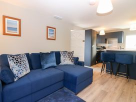 A living room with a sofa and kitchen island at Seaspray in Beadnell