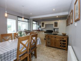 A kitchen with dining table and cabinets at 1 Maes Y Ffynnon in Llandegfan