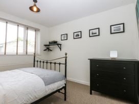 A bedroom with a bed, dresser, and shelf at 1 Maes Y Ffynnon Llandegfan