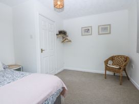 A bedroom with a bed and a chair at 1 Maes Y Ffynnon in Llandegfan