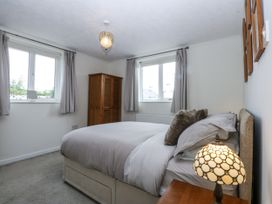 A bedroom with a bed and windows at 1 Maes Y Ffynnon in Llandegfan