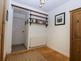 A hallway with books on a shelf and a door at 1 Maes Y Ffynnon Llandegfan