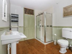 A bathroom with a sink, toilet, shower, and shelves at 1 Maes Y Ffynnon in Llandegfan