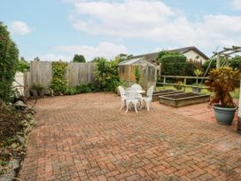 A garden with a table and chairs and a greenhouse at 1 Maes Y Ffynnon Llandegfan