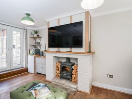 A living room with a fireplace and television at Firefly Cottage
