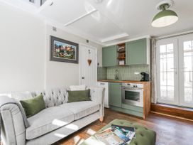 A living room with a sofa and kitchen area at Firefly Cottage