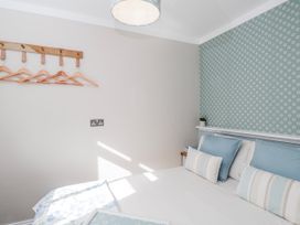A bedroom with a bed and wall hangers at Firefly Cottage