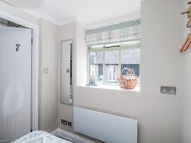 A bedroom with a window and a mirror at Firefly Cottage