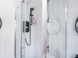 A shower with glass doors and fixtures in Firefly Cottage