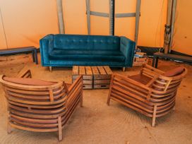 A seating area with a sofa and wooden chairs at Firefly Cottage