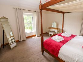 A bedroom with a four-poster bed and a dressing table at The Sycamores in Llawhaden near Narberth