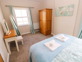 A bedroom with a bed, wardrobe, mirror, and chair at The Sycamores in Llawhaden near Narberth