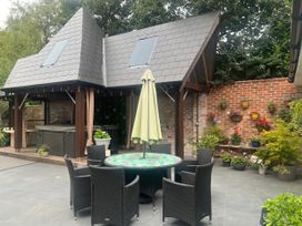 An outdoor seating area with a table and chairs next to a hot tub at 8 Church Road Ferndown