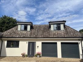 A house with a gravel driveway and two garage doors at 8 Church Road Ferndown