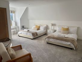 A bedroom with two beds and a desk at 8 Church Road Ferndown