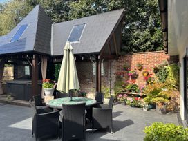 An outdoor area with a table and chairs, a hot tub, and a flower wall at 8 Church Road, Ferndown