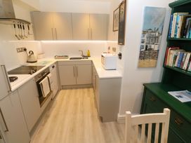 A kitchen with modern appliances and a wooden chair at Pelican Cottage St Ives