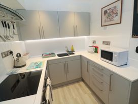 A kitchen with sink, microwave, kettle, and cooktop at Pelican Cottage St Ives