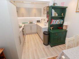A kitchen with cabinets and a green bookshelf at Pelican Cottage in St Ives