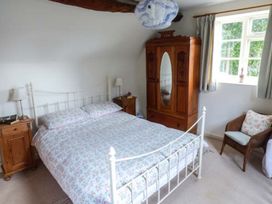 A bedroom with a bed, nightstands, and a wardrobe at The Smithy in Lucton near Mortimers Cross
