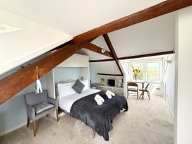 A bedroom with a bed, chair, and table at Crows Nest, St Ives