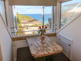 A dining room with a table, glasses, and a bottle at Seagulls Nest in St Ives