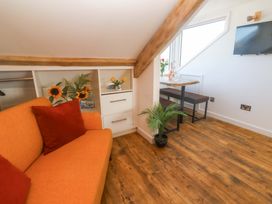 A living room with a sofa, dining table, and television at Seagulls Nest in St Ives