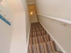 A staircase with striped carpet and a handrail at Seagulls Nest in St Ives