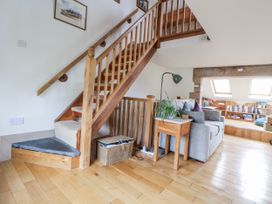 A living room with a staircase and sofa at The Hayloft in Bodelwyddan