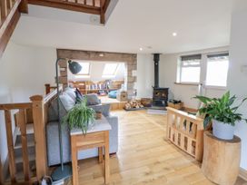 A living room with a wood stove and bookshelves at The Hayloft in Bodelwyddan