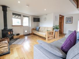 A living room with a stove, sofa, and television at The Hayloft in Bodelwyddan